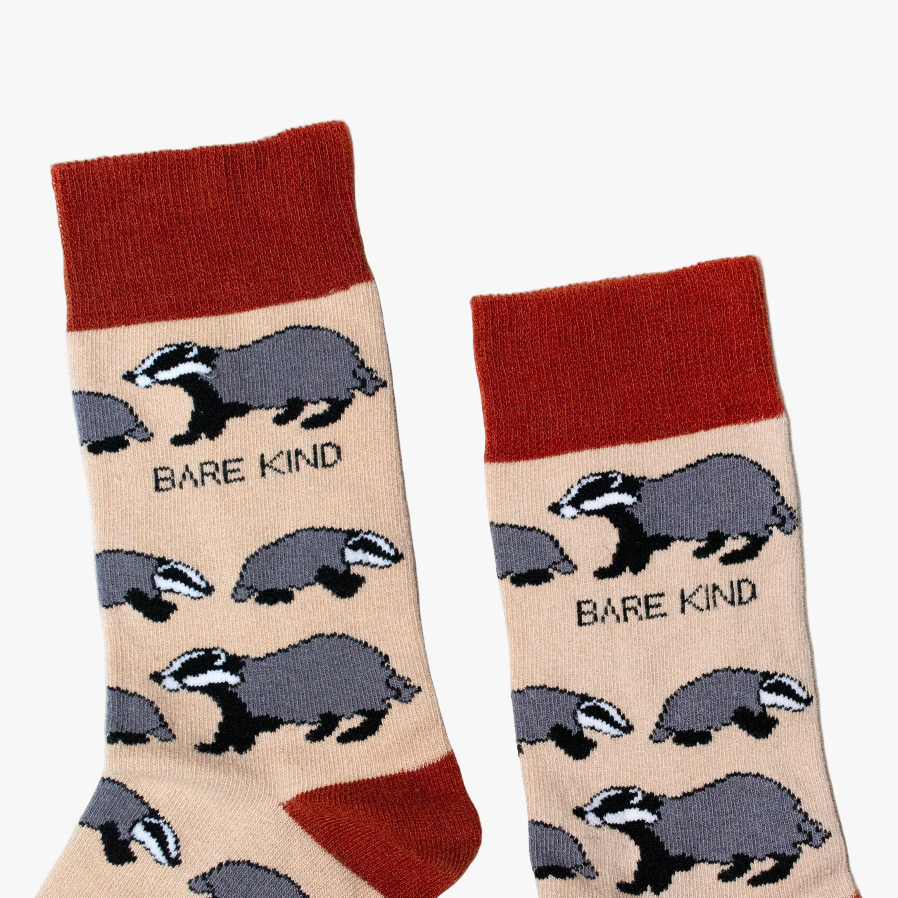 Pair of socks with badger illustrations and 'Bare Kind' text on a beige background