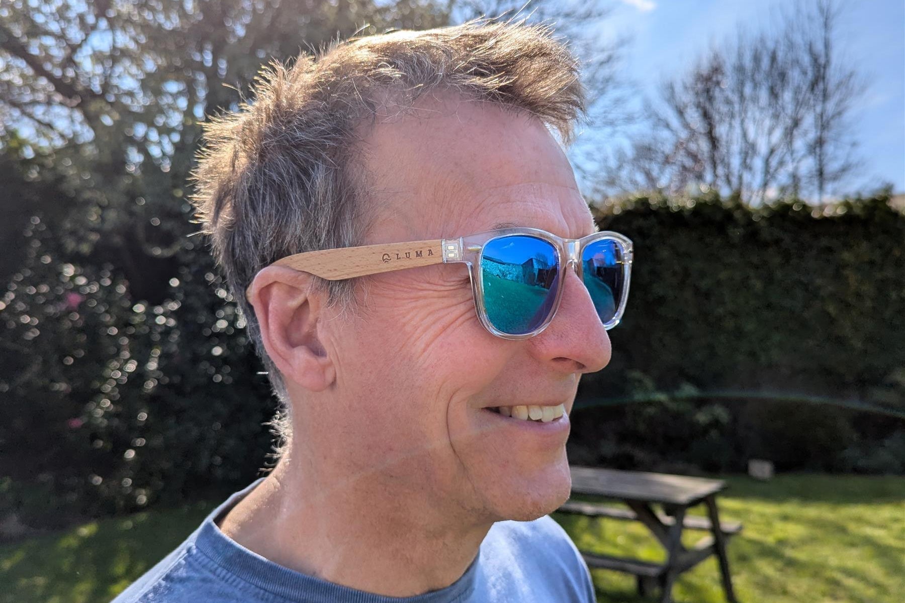 man wearing sunglasses with wooded les and clear plastic rims.