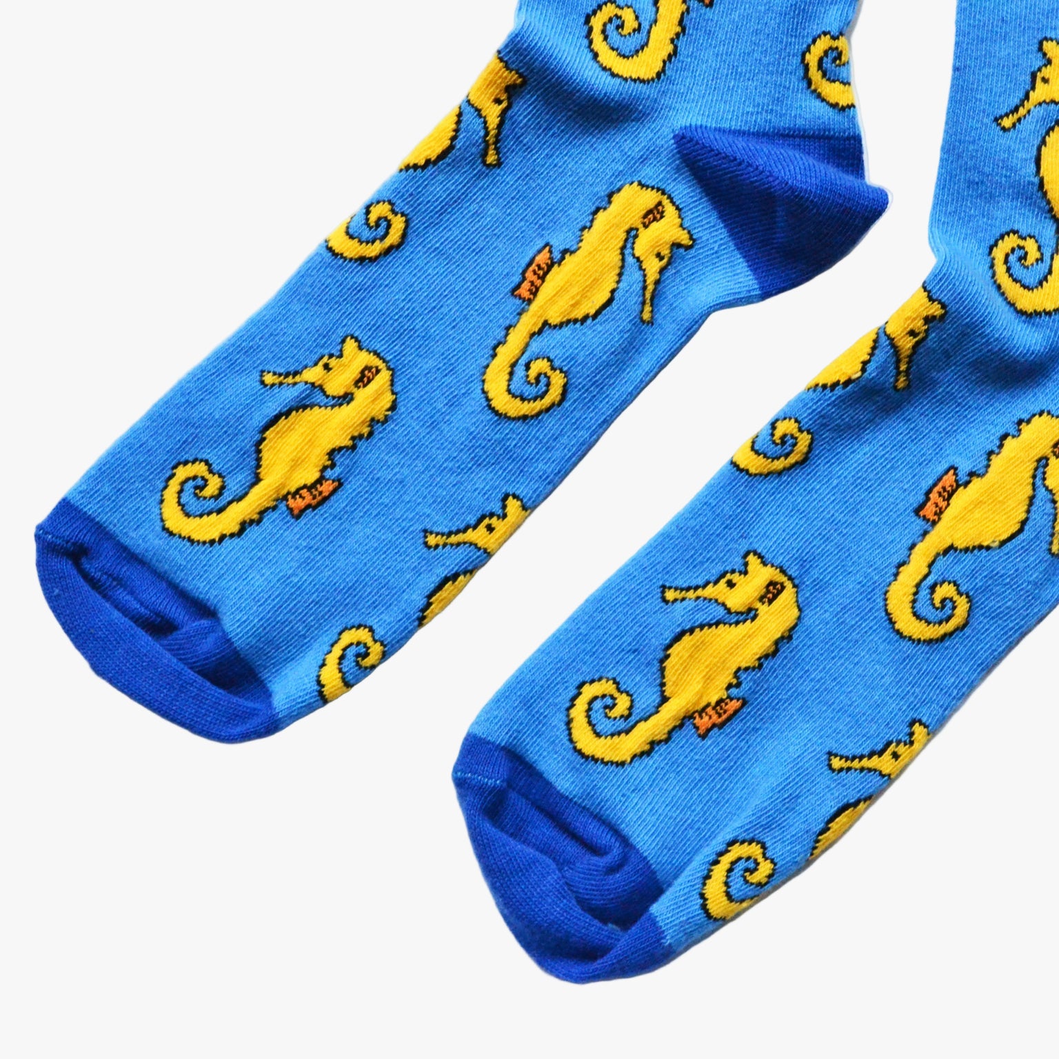 Blue socks with yellow seahorse patterns on a white background