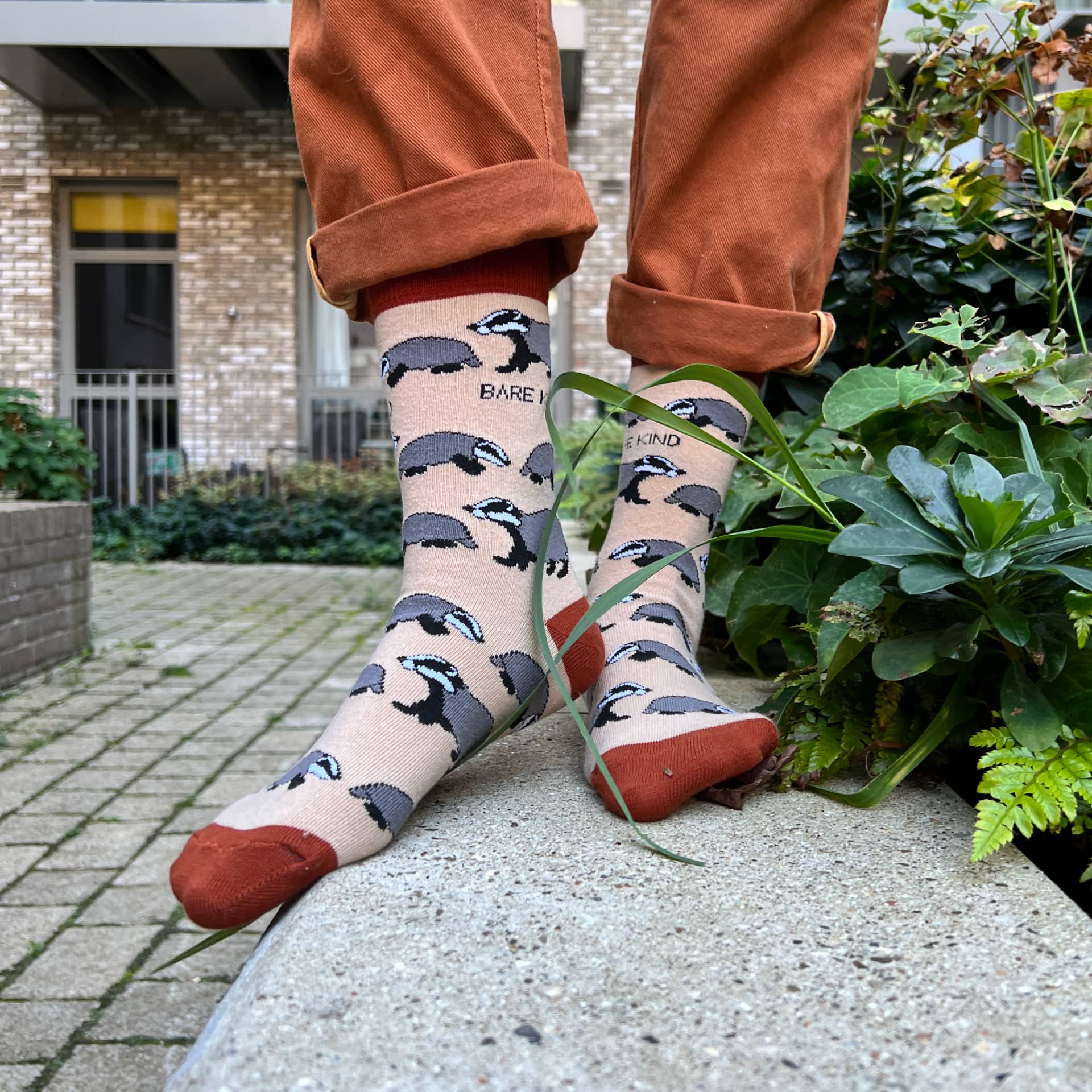 Person wearing socks with animal patterns outdoors on a stone ledge.