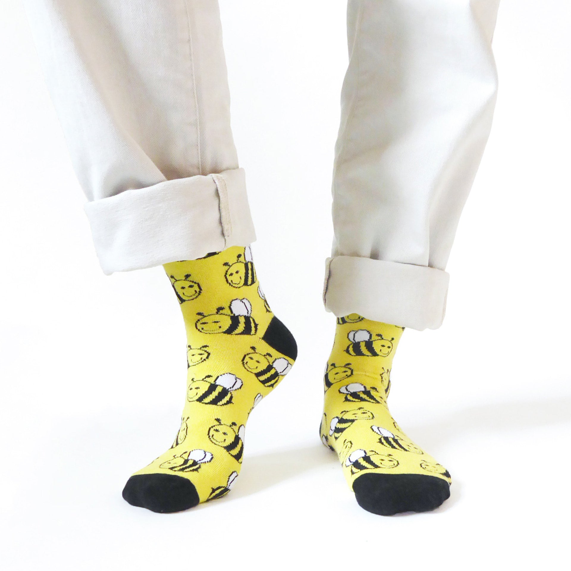 Yellow socks with bee pattern worn by a person on a white background