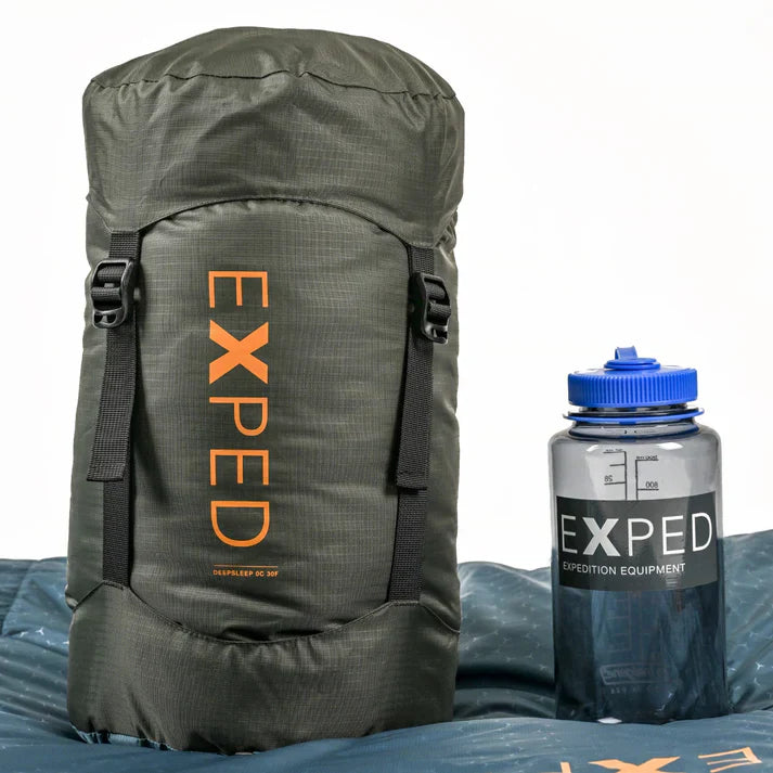 Green backpack and water bottle with 'Exped' branding on a white background