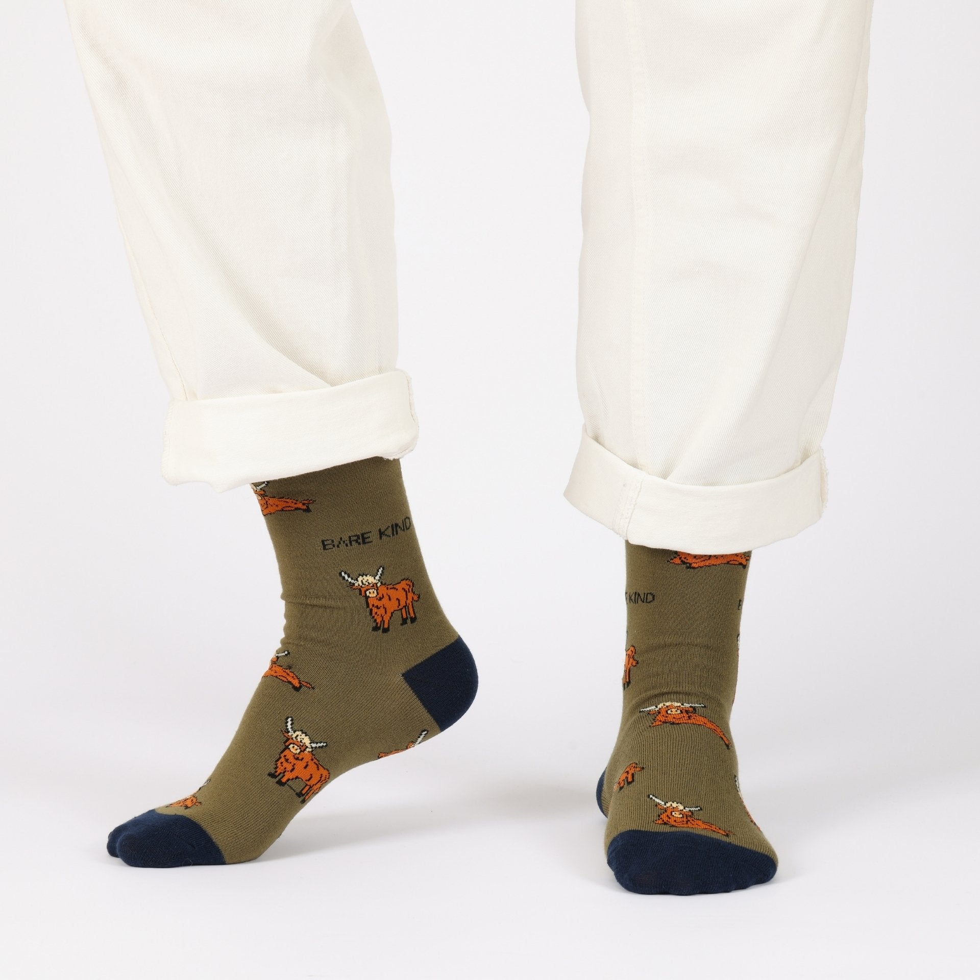 Green socks with orange designs worn with white pants on a white background
