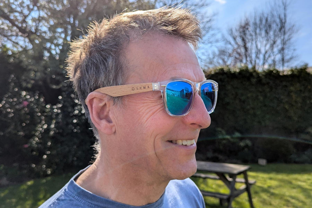 man wearing sunglasses with wooded les and clear plastic rims.