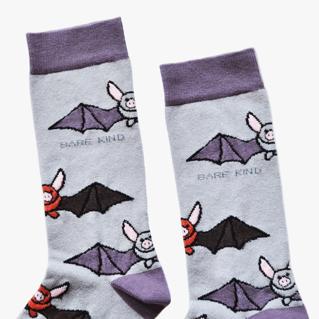 Pair of socks with bat illustrations and 'Bare Kind' text on a light gray background