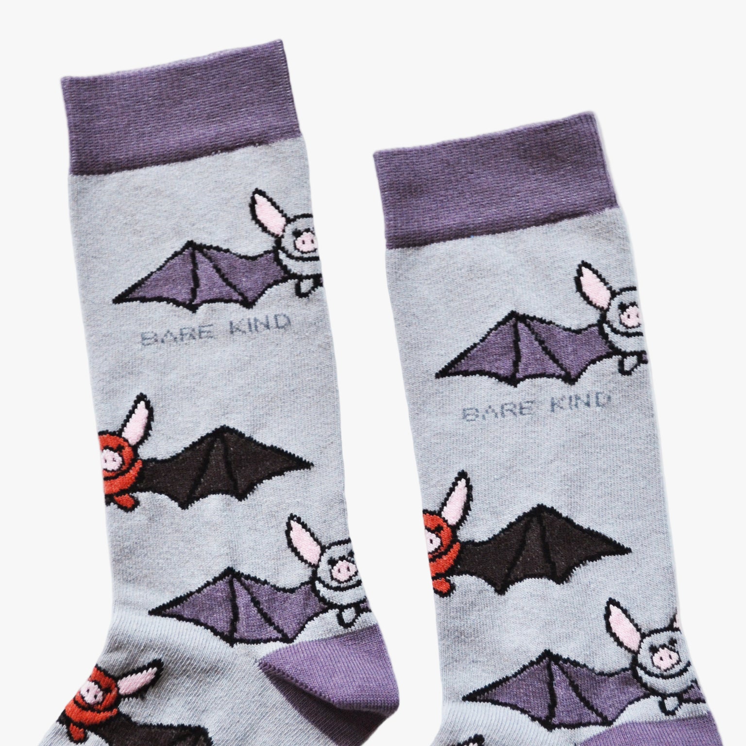 Pair of socks with bat illustrations and 'Bare Kind' text on a light gray background