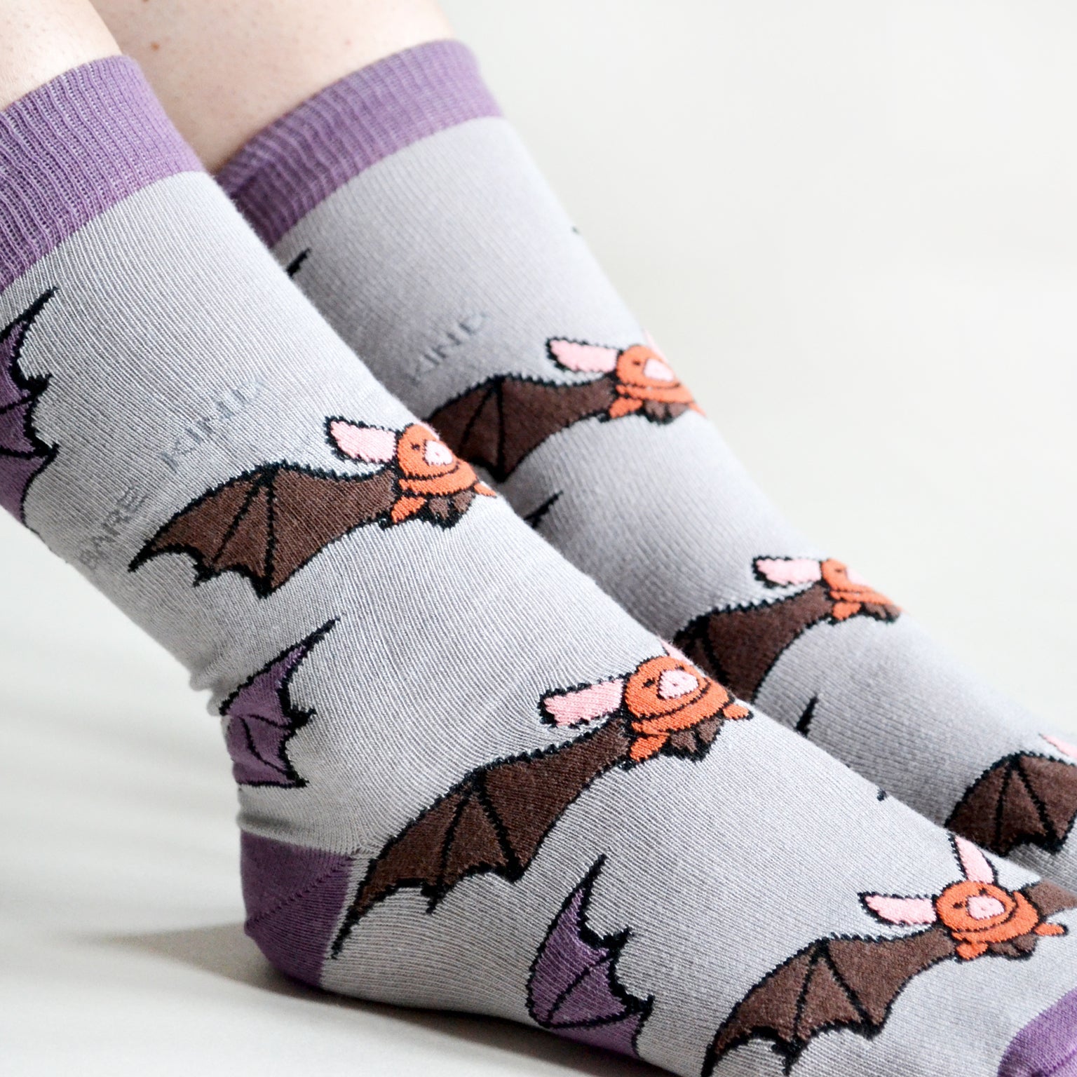 Gray socks with bat designs worn on a white background