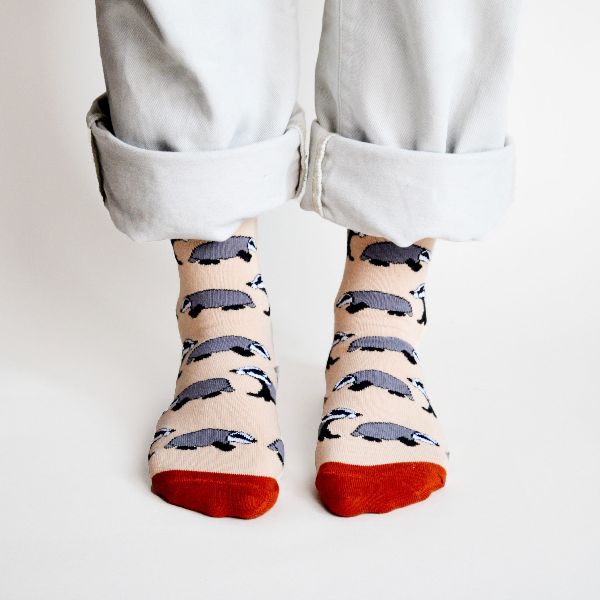 Person wearing socks with badger pattern and red toes on a plain background