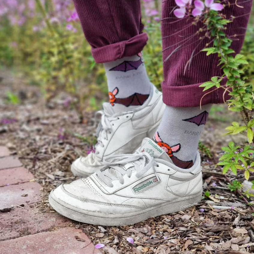 White Reebok sneakers with gray socks featuring cartoon characters, worn outdoors on a natural background.