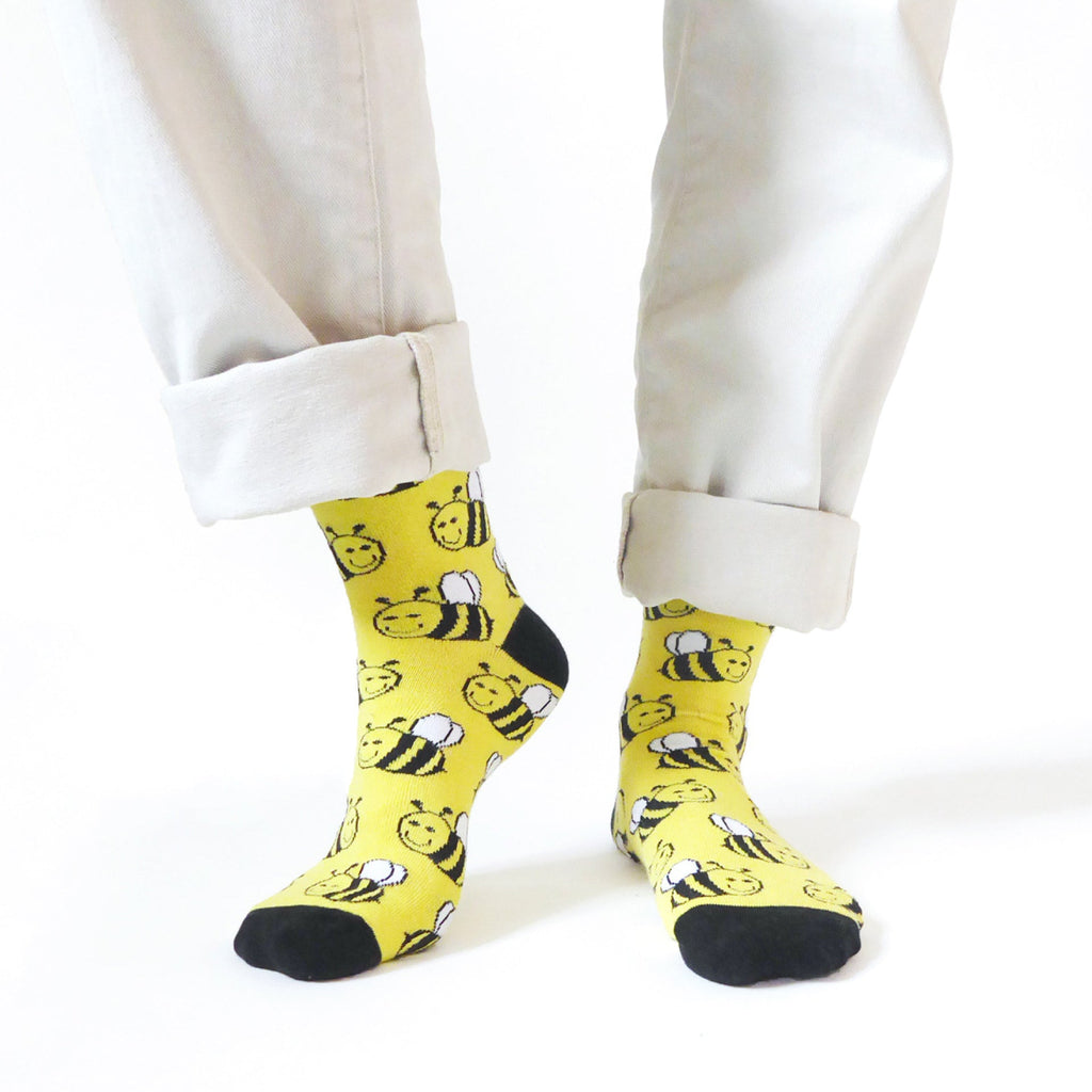 Yellow socks with bee pattern worn by a person on a white background
