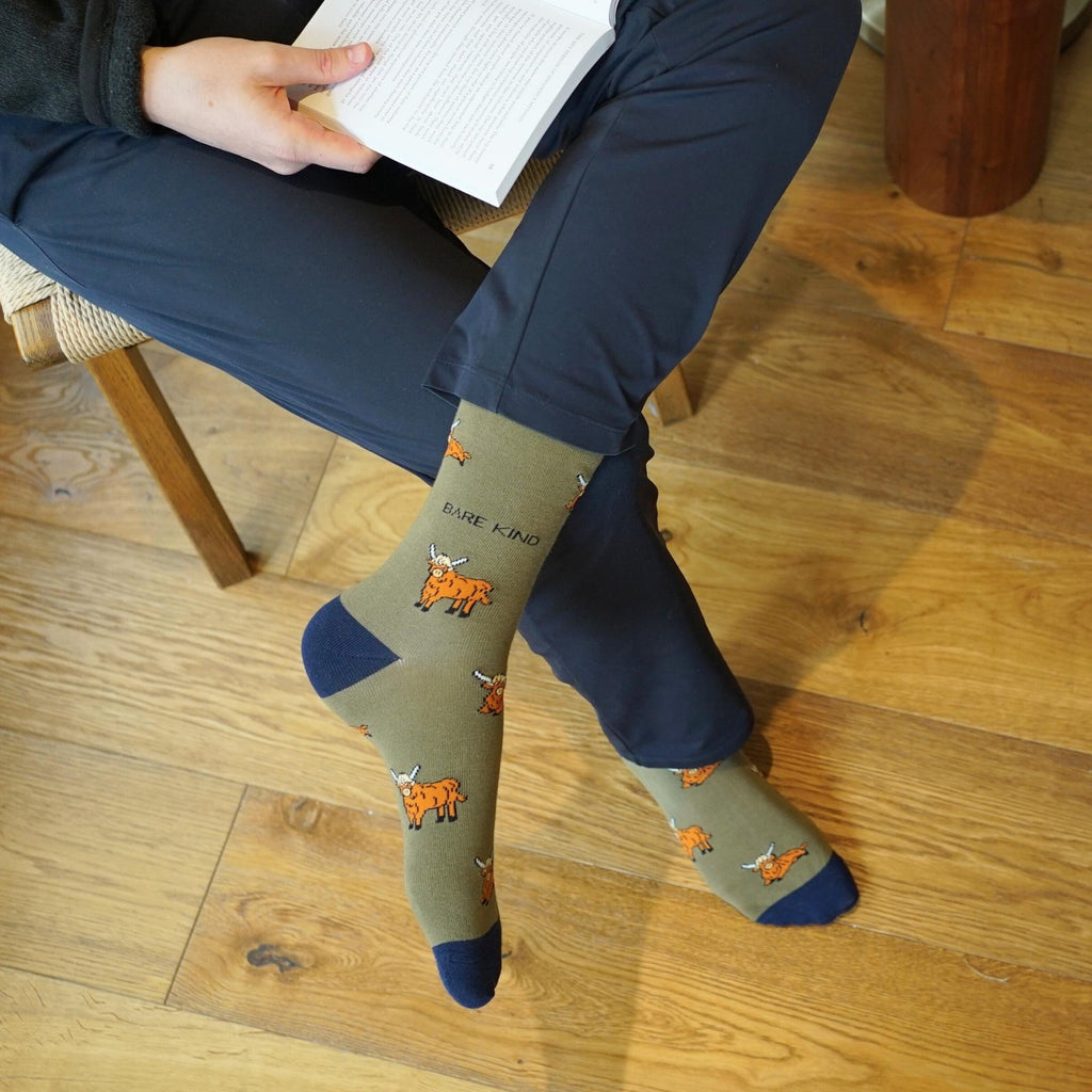 Person wearing socks with animal designs and text, sitting on a wooden floor.