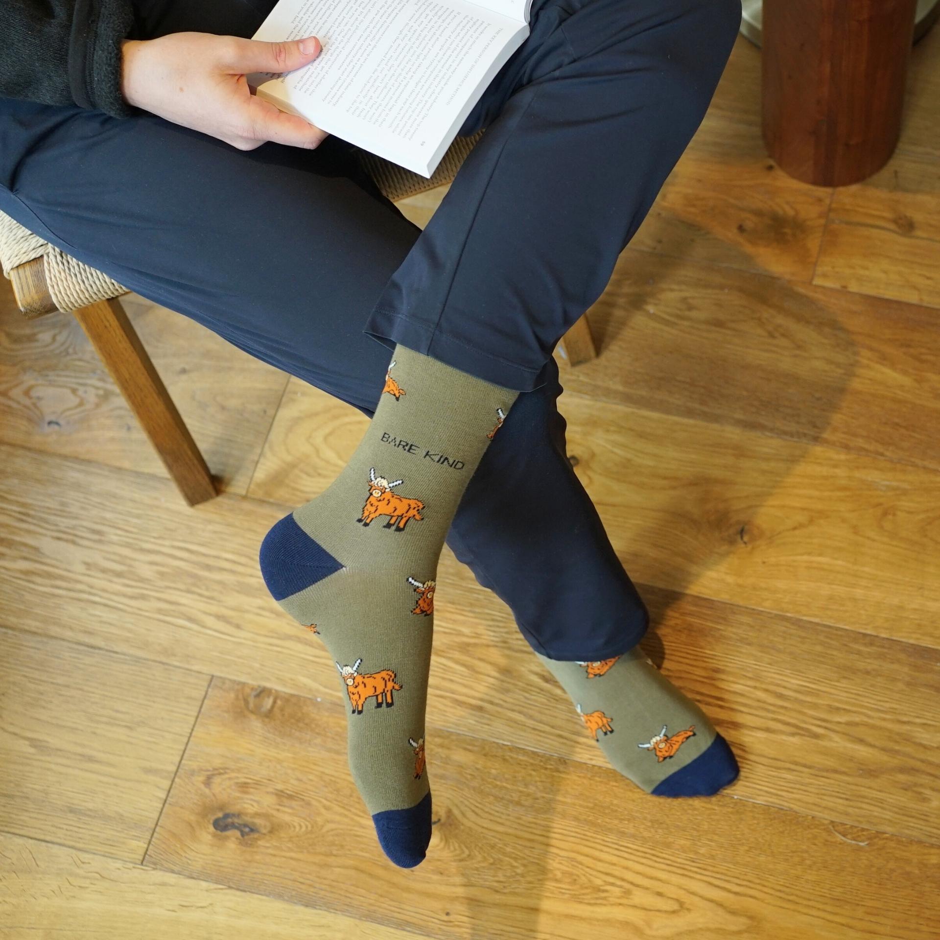 Person wearing socks with animal designs and text, sitting on a wooden floor.