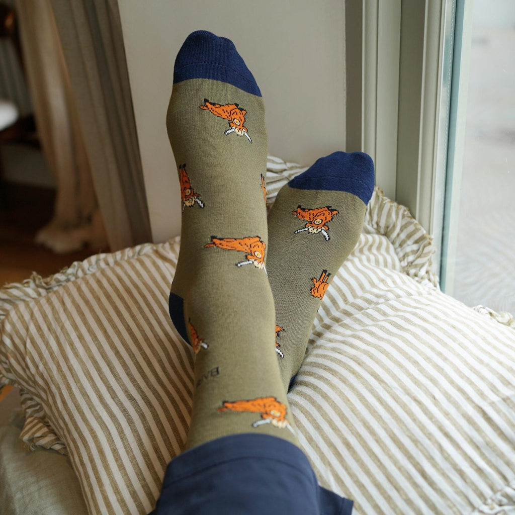Person wearing socks with fox patterns on a striped pillow