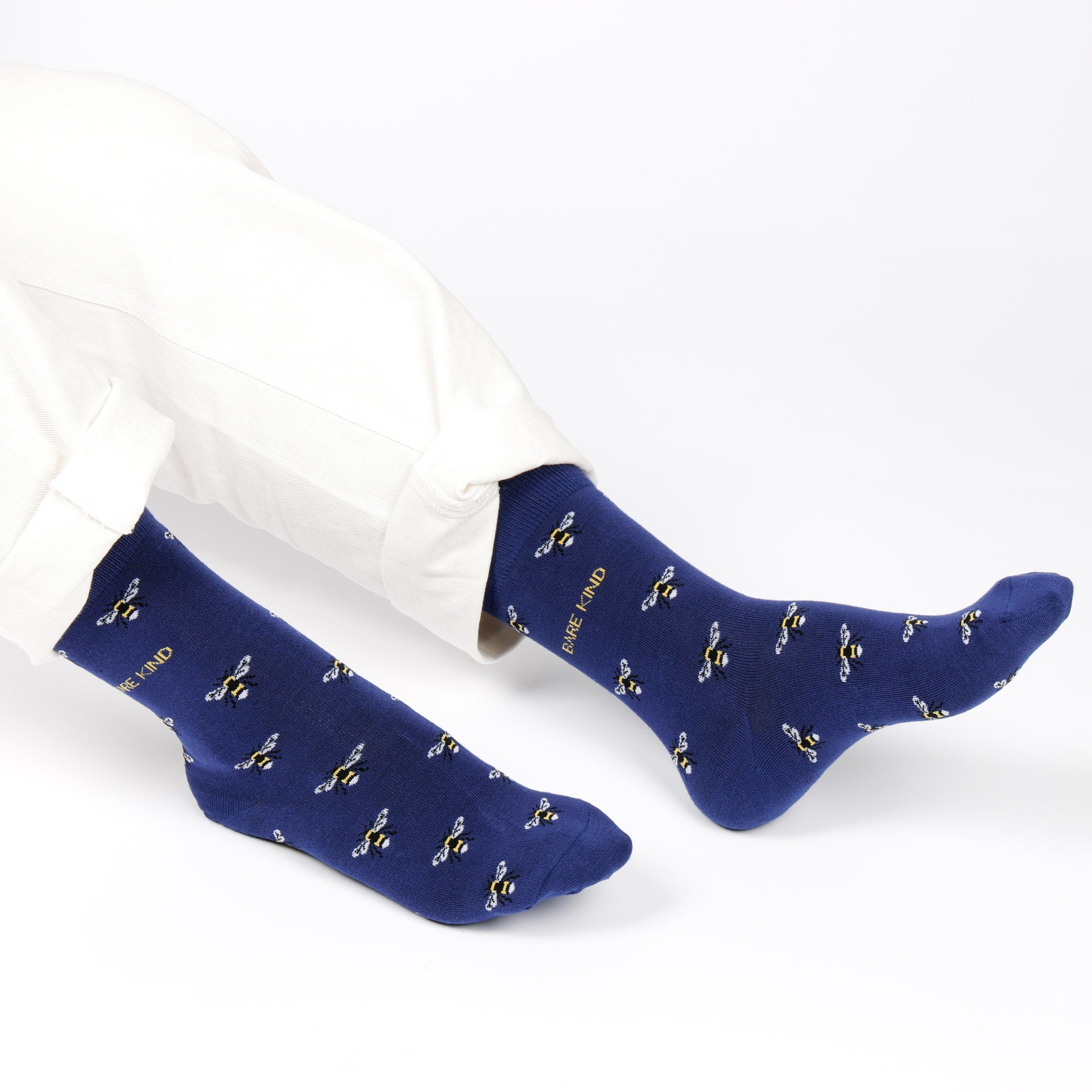 Blue socks with bee pattern worn by a person on a white background